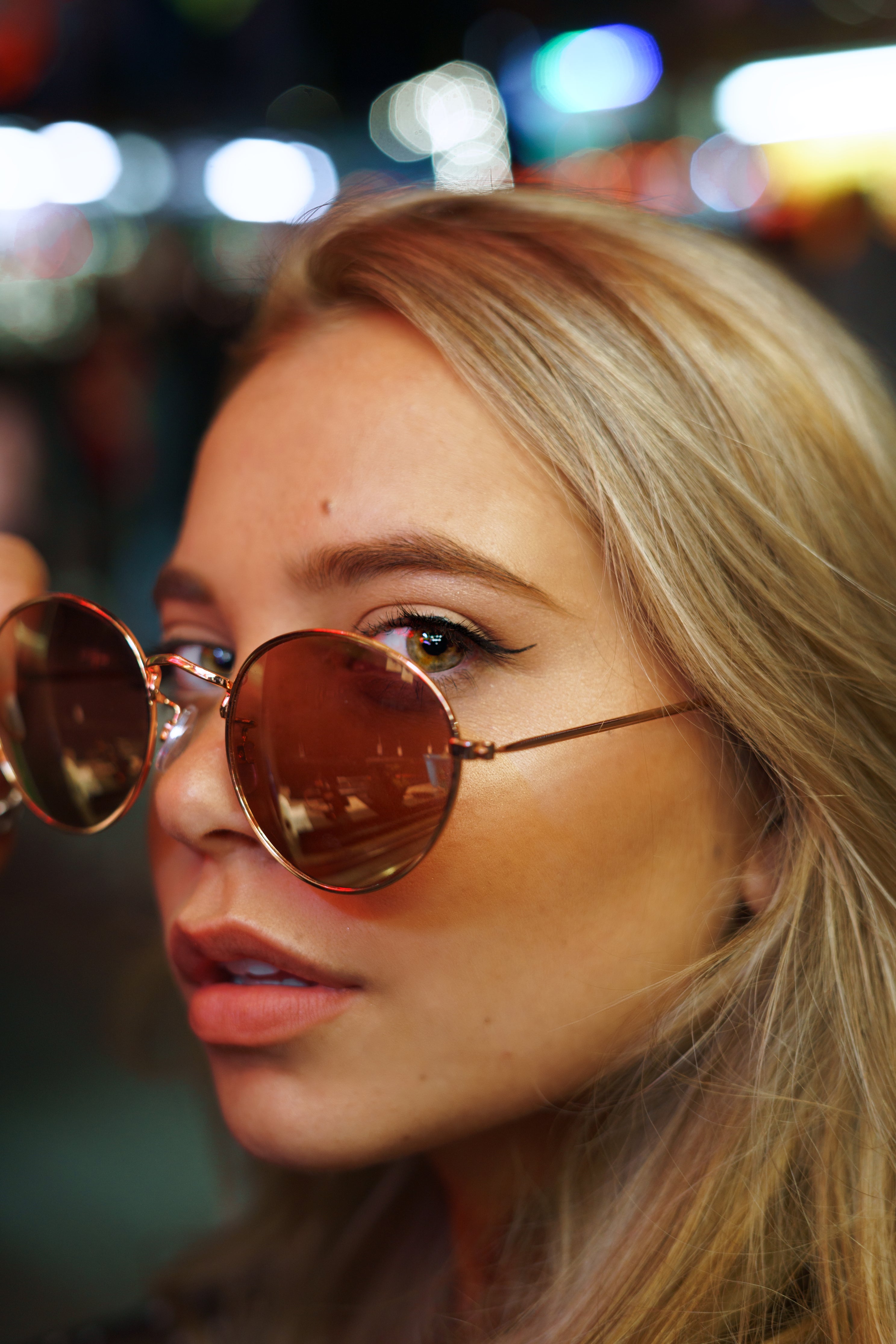 Close-up of a person wearing round sunglasses with a blurred background